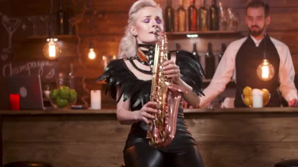 Beautiful woman in a dark leather stage costume performs a song on a saxophone — Stock Video