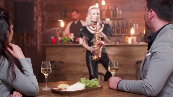 Pareja escuchando una actuación de saxofón en vivo — Vídeos de Stock