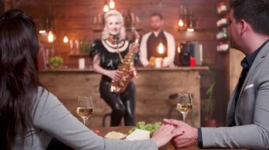 Genç bir çift, bir kadın saksafoncuyu alkışlıyor.