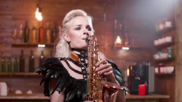 Vrouw in een donker lederen kostuum voert een lied op een saxofoon — Stockvideo