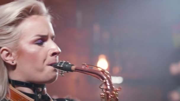 Close up portrait of a blonde female performing a song on a saxophone — Stock Video