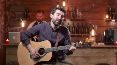 Genç adam akustik gitarla şarkı söylüyor.
