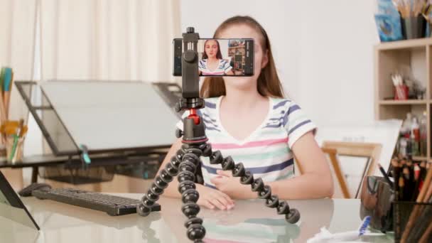 Смартфон на штативе, снимающий разговор молодой девушки — стоковое видео