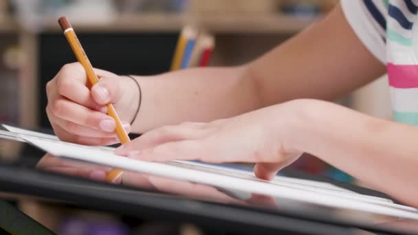 Las niñas manos dibujar algo en un pedazo de papel con un lápiz — Vídeo de stock