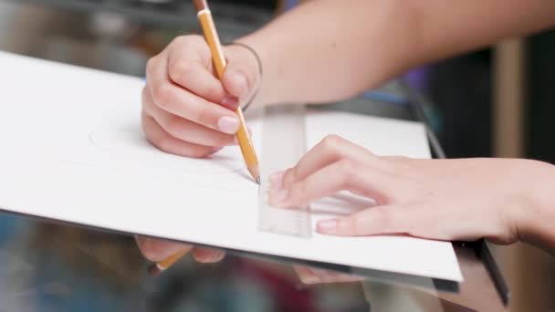Jovencitas manos dibujando una línea en un pedazo de papel blanco usando una regla y un lápiz — Vídeo de stock