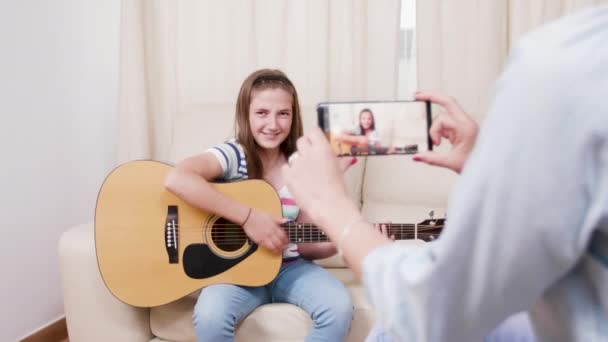 Η μητέρα κάνει ένα βίντεο με τη νεαρή κόρη της να παίζει σε μια ακουστική κιθάρα — Αρχείο Βίντεο