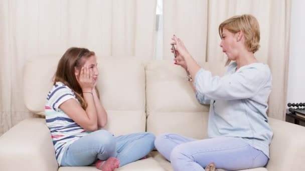 Mother taking pictures of her daughter while relaxing on a sofa — Stock Video