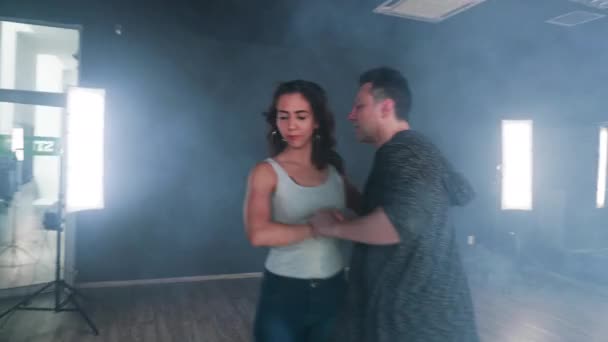 Pareja bailando en luminoso estudio lleno de humo — Vídeo de stock