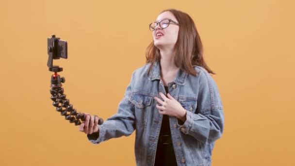 Молодой подросток-блогер делает видео с помощью гибкого штатива и ее смартфона — стоковое видео
