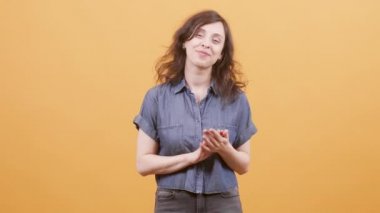 Güzel kadın sarı arka plan üzerinde alkışlıyor