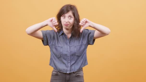 Young woman over yellow background showing thumbs down sign — 비디오