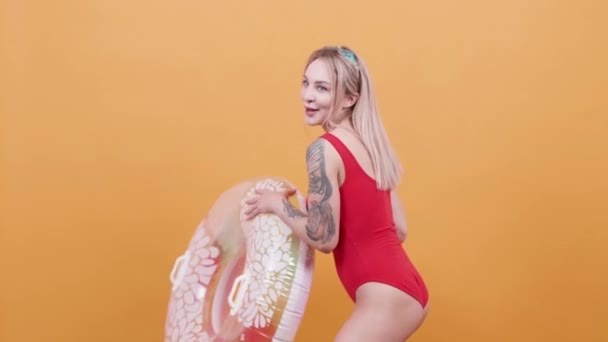 Femme blonde sexy en maillot de bain une pièce jouant avec un anneau de natation 