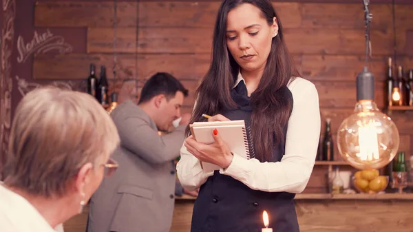 Mujer mayor diciendo a los camareros lo que quiere — Foto de Stock