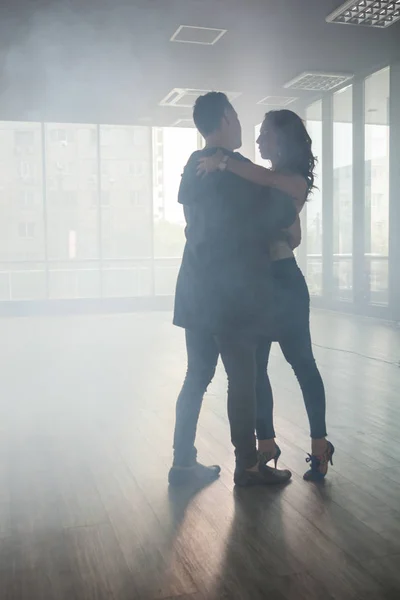 Пара влюбленных танцующих кизомбу в танцевальной комнате, полной дыма — стоковое фото