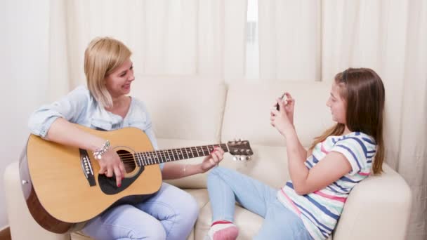 Akustik gitar çalan annesinin fotoğraflarını çeken genç kız — Stok video