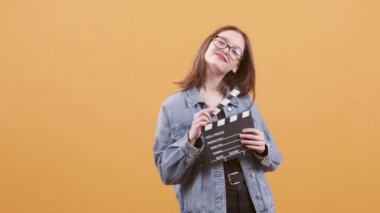 Güzel genç kız bir clapperboard tutun ve kameraya gülümsüyor