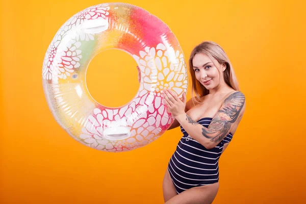 Krásná mladá žena v plaveckém obleku s barevným plaveckým kroužkem připraveným na letní prázdniny — Stock fotografie