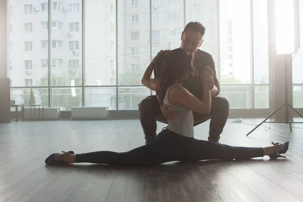 Dançarino masculino olhando para seu parceiro enquanto ela faz um deslizamento na sala de prática — Fotografia de Stock