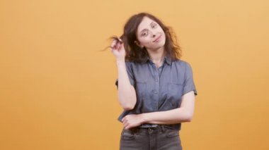 Gülümseyen ve sarı arka planda saçlarıyla oynayan güzel bir kız.