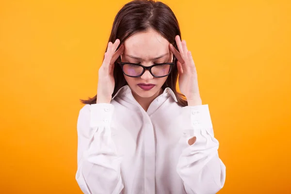 Porträtt av vacker ung flicka med smärtsam huvudvärk i studion över gul bakgrund — Stockfoto
