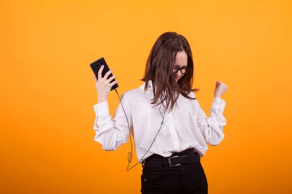 Mooie jonge vrouw met hoofdtelefoon luisteren naar muziek en zingen op kleur achtergrond — Stockfoto