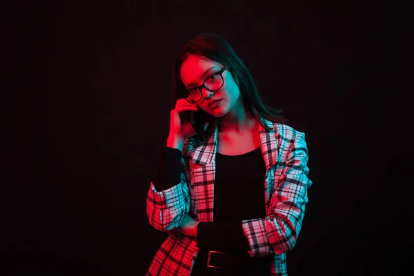 Elegantní mladá dívka mluvící na telefonu ve studiu s barevným osvětlením — Stock fotografie