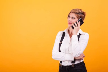 Çekici genç kadın sarı arka plan üzerinden telefonda konuşurken başka bir şey hakkında düşünme.
