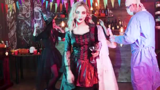 Sexy bruja sosteniendo un vaso de sangre en sus manos y baila lentamente en una fiesta de Halloween — Vídeos de Stock