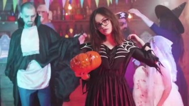 Cadı kostümlü çekici bir kız elinde bir fenerle dans ediyor.