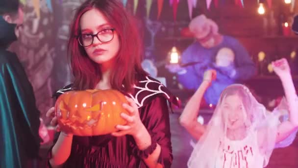 Девочка-подросток танцует в замедленной съемке с резной тыквой в руке на вечеринке в честь Хэллоуина — стоковое видео