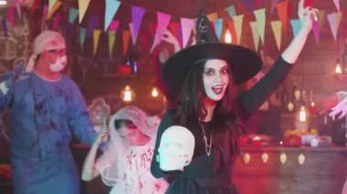 Güzel gülüşü olan genç bir kadın cadılar bayramı partisinde cadı kılığında dans eder.