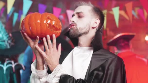 Man in vampire outfit holds a carved pumpkin head in his hand — Stock Video