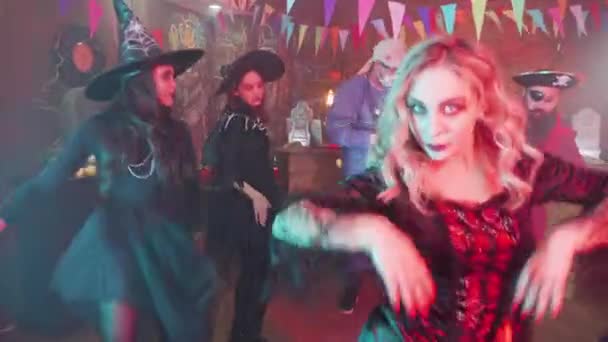 Enchantress in zwarte sensuele outfit dansen met haar enge vrienden op een Halloween feest — Stockvideo