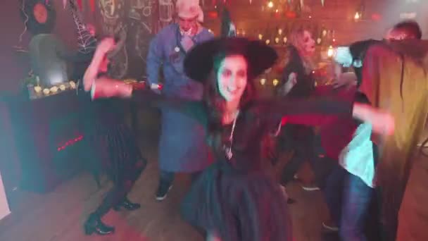 Femme en costume de sorcière maléfique dansant au milieu d'un groupe d'amis célébrant Halloween — Video