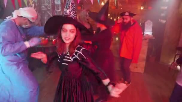 Tiener meisje in boze heks kostuum dansen in het midden van een groep vrienden vieren Halloween — Stockvideo