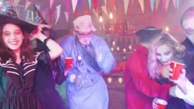 Cadılar Bayramı kıyafetleri içinde bir barda dans eden genç insanlar.