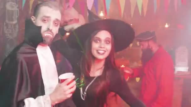 Молодые люди пьют и танцуют на Хэллоуинской вечеринке в местном пабе — стоковое видео