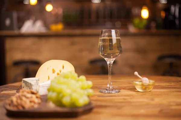 Fehér borosüvegek fehér szőlővel és sajttal fából készült asztalon — Stock Fotó
