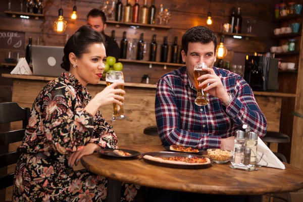 Glückliches Paar trinkt Bier und isst Pizza. — Stockfoto