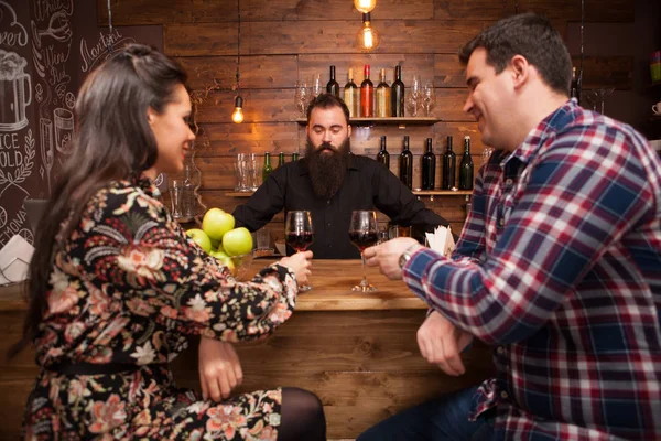 Bonito barman conversando com clientes no balcão de bar em um pub . — Fotografia de Stock
