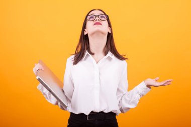 Pretty genç kız dizüstü bilgisayar tutan ve sarı arka plan üzerinde stüdyoda arıyor