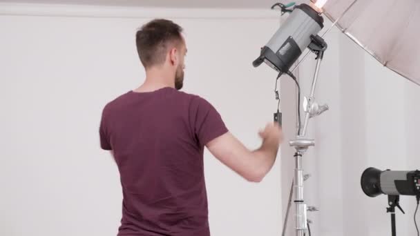 Fotógrafo profissional trabalhando e configurando os flashes antes de uma sessão de fotos de moda — Vídeo de Stock