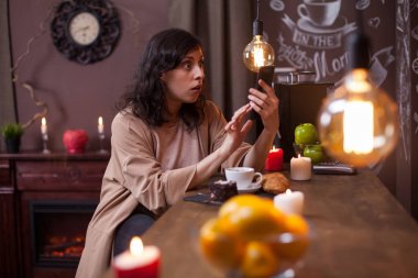 Bir kafede bir bar tezgahında oturan şok genç kadının portresi telefonuna bakıyor