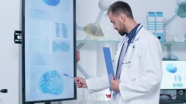 Doktor onun modern ofis veya araştırma merkezinde büyük ekran Tv bakıyor