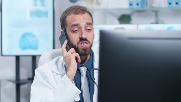 Ruční snímek mladého lékaře s rozhovorem na telefonu — Stock video