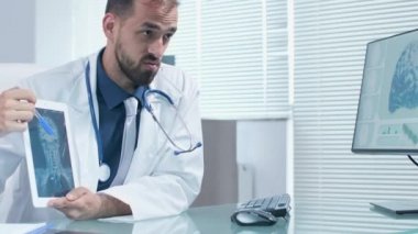 Profesyonel doktor elinde bir Pc tablet tutan ve X Ray tarak bir şey açıklayan