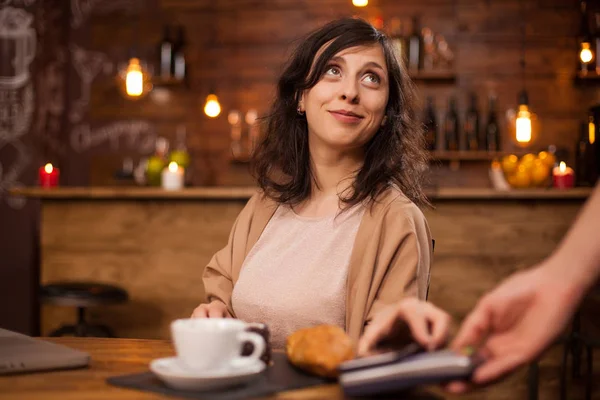 바리스타를 올려다보고 커피숍에서 현대적인 지불을 사용하여 커피를 지불하는 아름다운 여성의 초상화 — 스톡 사진