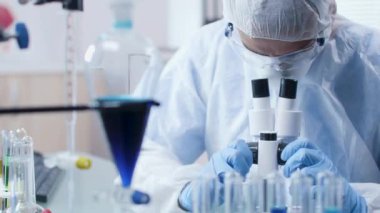 Modern laboratuvarbiliminde tulum bilim adamı mikroskopa bakıyor