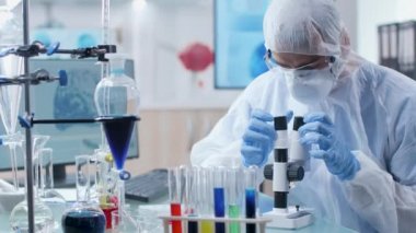 Üst düzey laboratuvarda mikroskoba bakan kapaklı kimyager