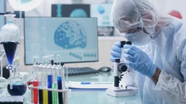 Modern ve yüksek son güvenlik laboratuarında bir bilim adamı mikroskobu araştırıyor.